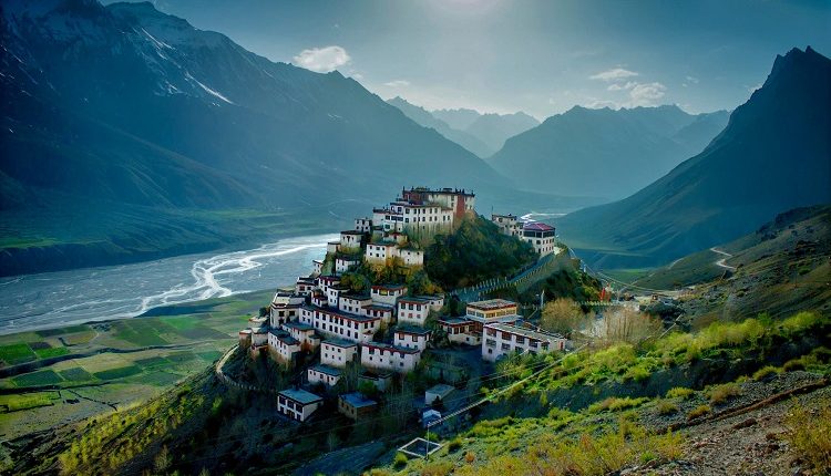 Spiti River meandering through valley beneath ancient monastery and towering peaks.